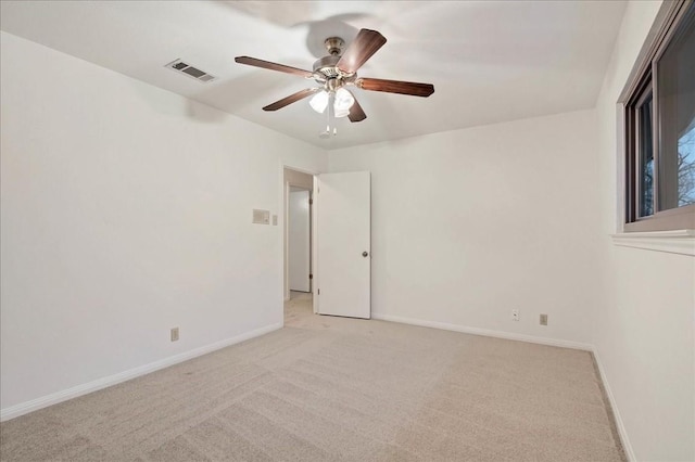 empty room featuring baseboards, ceiling fan, visible vents, and light colored carpet