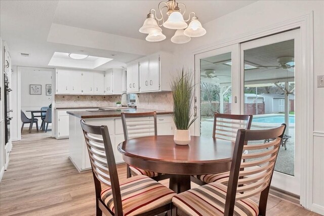 dining room featuring a tray ceiling, an inviting chandelier, light wood-style floors, and visible vents