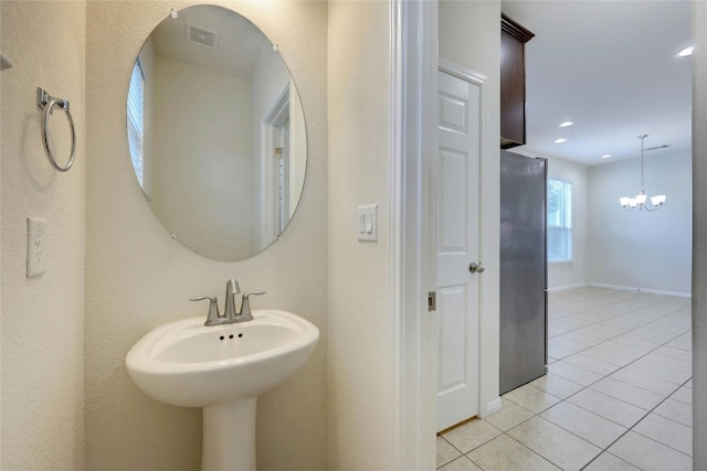 bathroom featuring tile patterned floors, sink, and a notable chandelier