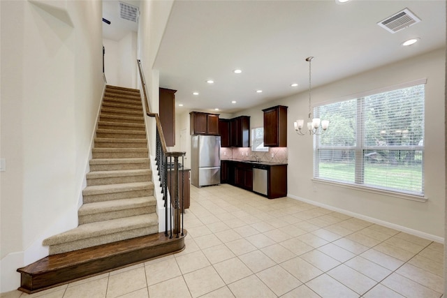 kitchen featuring backsplash, appliances with stainless steel finishes, a chandelier, light tile patterned flooring, and decorative light fixtures