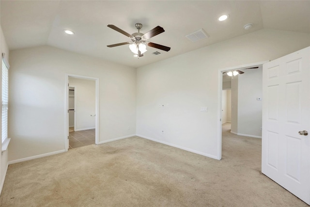 empty room with ceiling fan, light colored carpet, and vaulted ceiling