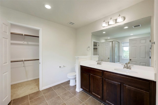 bathroom with vanity, toilet, tile patterned floors, and walk in shower