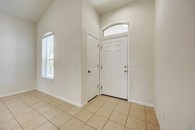 foyer entrance with lofted ceiling and light tile patterned floors