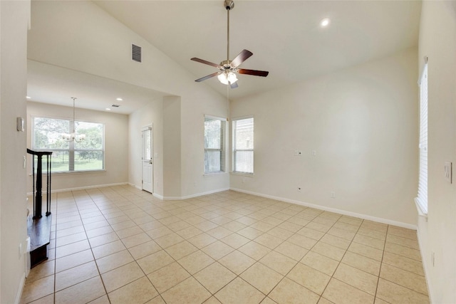 empty room featuring high vaulted ceiling, light tile patterned flooring, plenty of natural light, and ceiling fan with notable chandelier