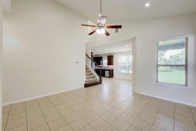 unfurnished room with high vaulted ceiling, light tile patterned flooring, and ceiling fan with notable chandelier