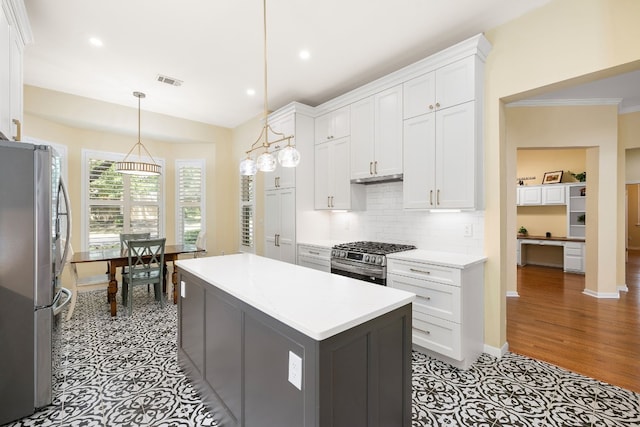 kitchen with appliances with stainless steel finishes, a center island, white cabinets, and decorative light fixtures