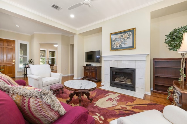 living room with ceiling fan, ornamental molding, light hardwood / wood-style flooring, and a fireplace