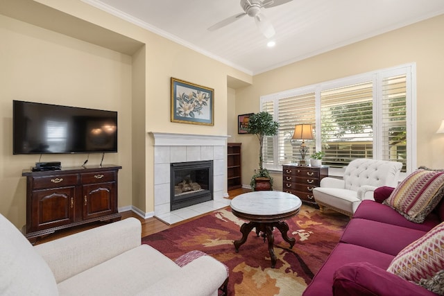 living room with light hardwood / wood-style floors, crown molding, a tile fireplace, and ceiling fan