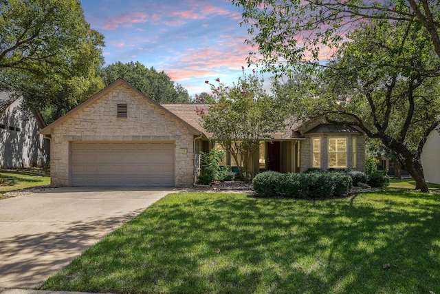 view of front facade with a garage, concrete driveway, a lawn, and stone siding