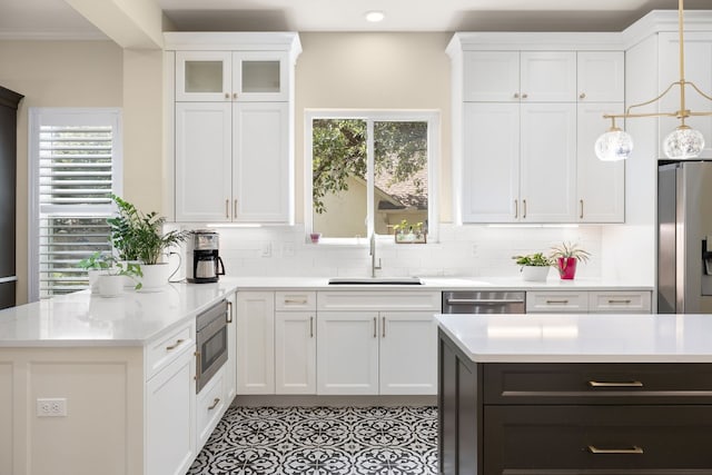 kitchen with sink, white cabinetry, appliances with stainless steel finishes, pendant lighting, and decorative backsplash