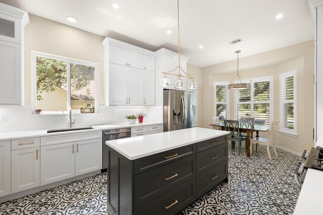 kitchen featuring white cabinets, backsplash, appliances with stainless steel finishes, pendant lighting, and sink