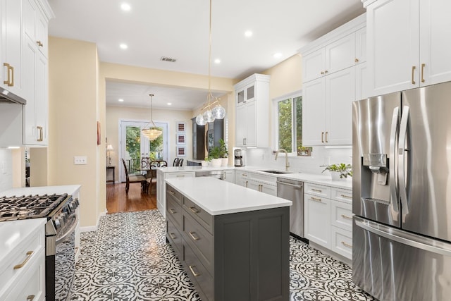 kitchen with white cabinets, a kitchen island, sink, decorative light fixtures, and stainless steel appliances