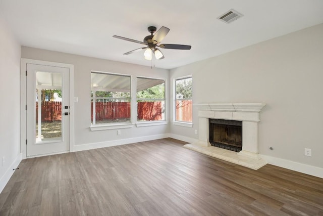 unfurnished living room featuring baseboards, wood finished floors, visible vents, and a high end fireplace