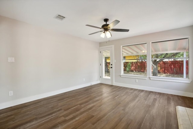 empty room featuring a ceiling fan, wood finished floors, visible vents, and baseboards