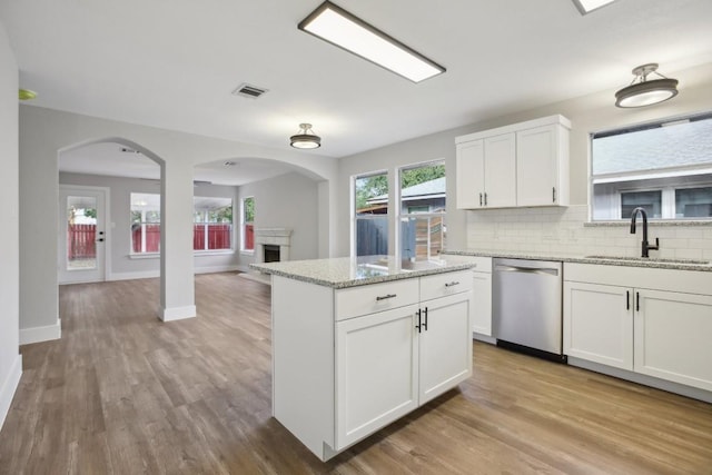 kitchen with light wood-style flooring, a sink, visible vents, decorative backsplash, and dishwasher