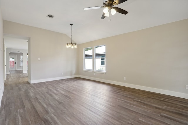 spare room with vaulted ceiling, dark hardwood / wood-style floors, and ceiling fan with notable chandelier