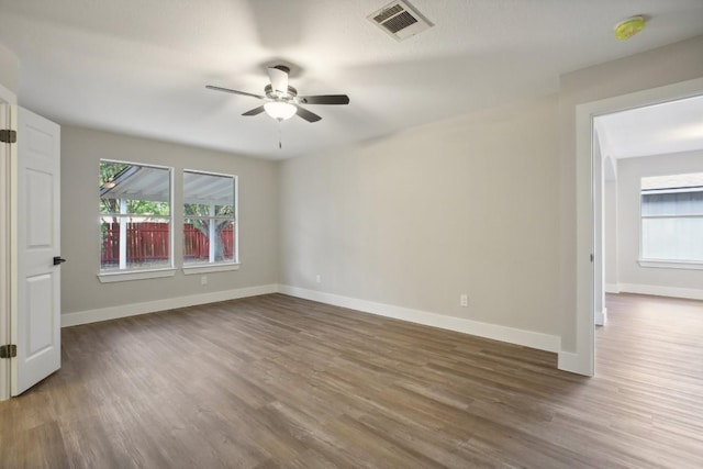 unfurnished room featuring visible vents, plenty of natural light, and wood finished floors