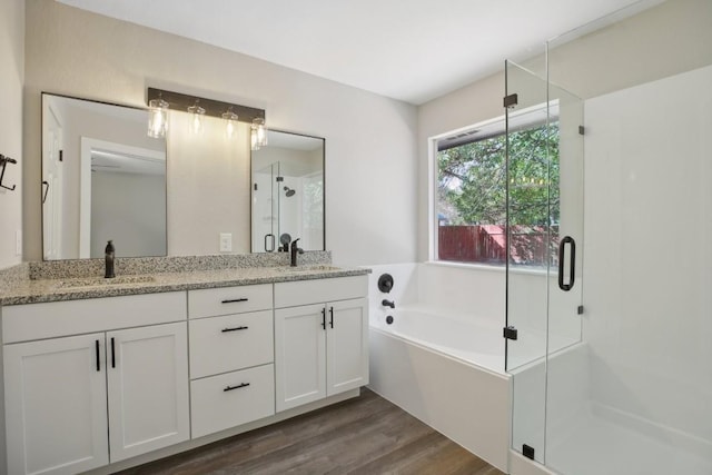 full bath with a garden tub, wood finished floors, a stall shower, and a sink