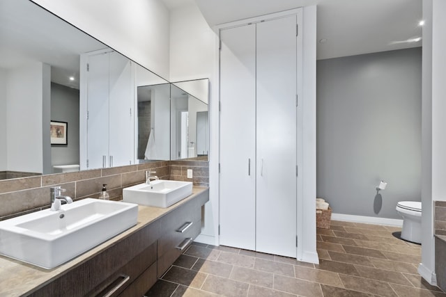 bathroom with vanity, decorative backsplash, and toilet