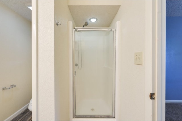 bathroom featuring toilet, a textured ceiling, a shower with shower door, and hardwood / wood-style floors