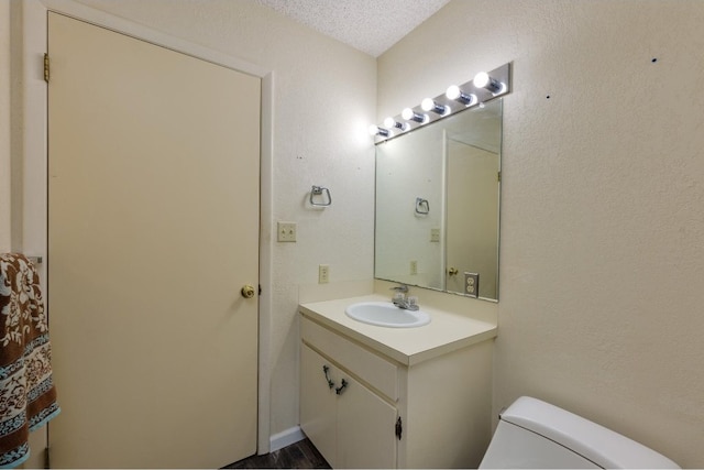 bathroom featuring toilet, a textured ceiling, vanity, and wood-type flooring