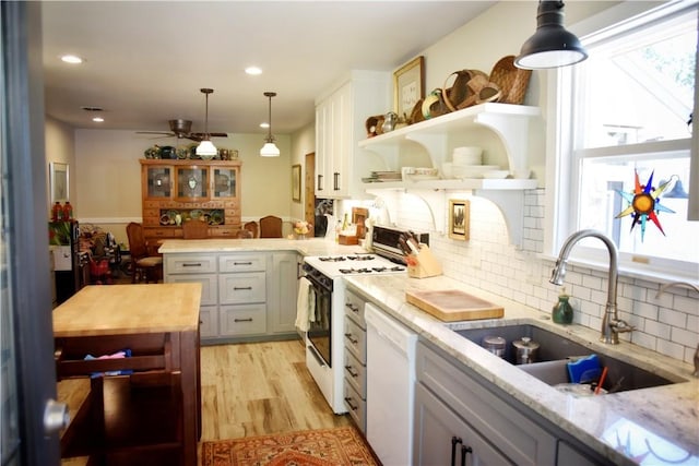 kitchen featuring plenty of natural light, white appliances, sink, and hanging light fixtures