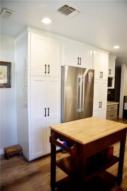 kitchen with high end refrigerator, white cabinets, and dark hardwood / wood-style floors