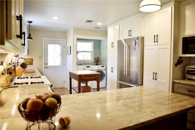 kitchen with white cabinets, stainless steel fridge, and light stone counters