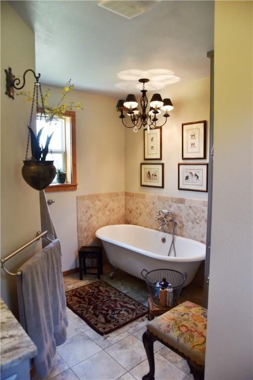 bathroom with tile patterned flooring, a tub to relax in, and an inviting chandelier