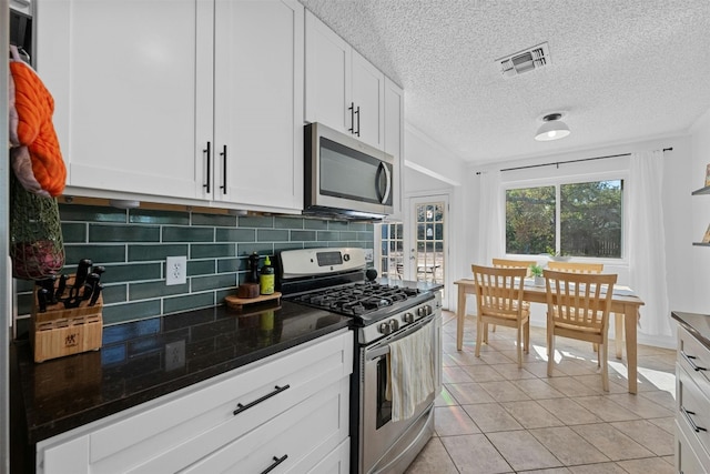 kitchen featuring stainless steel appliances, backsplash, light tile patterned floors, white cabinets, and a textured ceiling