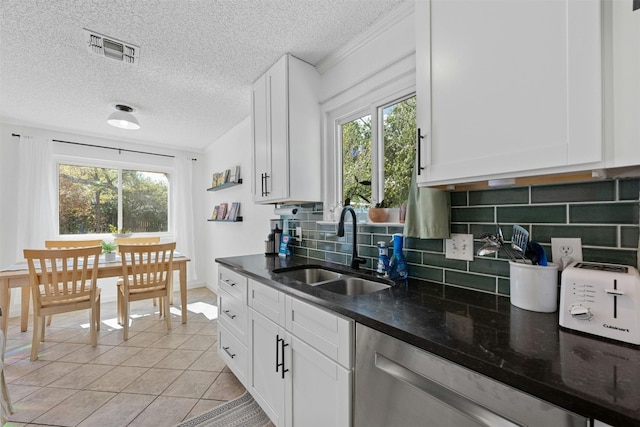 kitchen with tasteful backsplash, sink, white cabinets, dark stone countertops, and light tile patterned floors