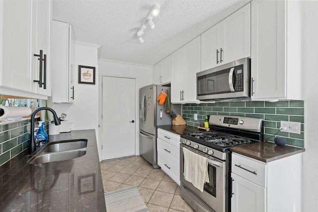 kitchen featuring sink, light tile patterned flooring, backsplash, stainless steel appliances, and white cabinets