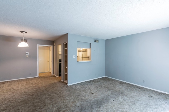 empty room with a textured ceiling and dark colored carpet