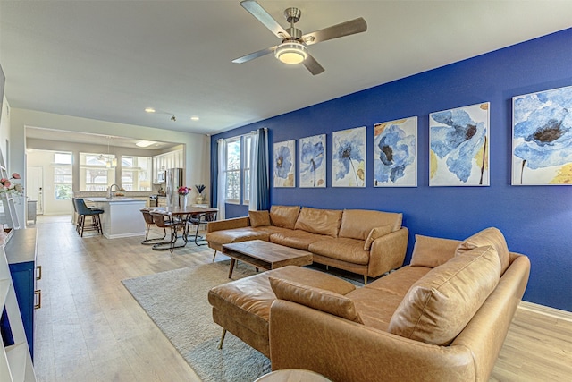 living room with ceiling fan, sink, and light wood-type flooring