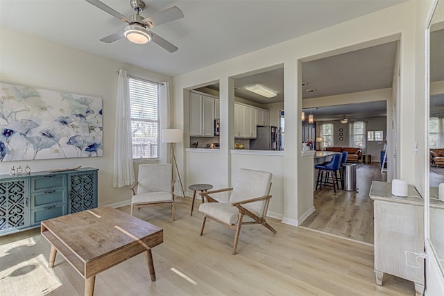 living area featuring light wood-type flooring and ceiling fan