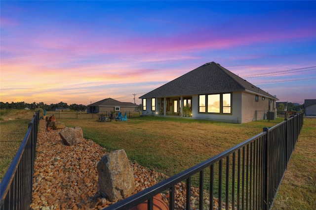 back house at dusk with a lawn