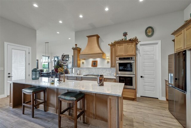 505 John Price St, Blanco, TX 78606 - kitchen featuring stainless steel appliances, recessed lighting, premium range hood, light wood finished floors, and light stone counters