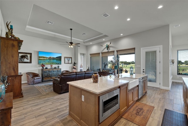 kitchen with light hardwood / wood-style floors, stainless steel appliances, sink, and a center island with sink