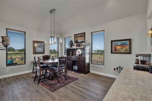 dining area featuring lofted ceiling, dark hardwood / wood-style floors, a chandelier, and plenty of natural light