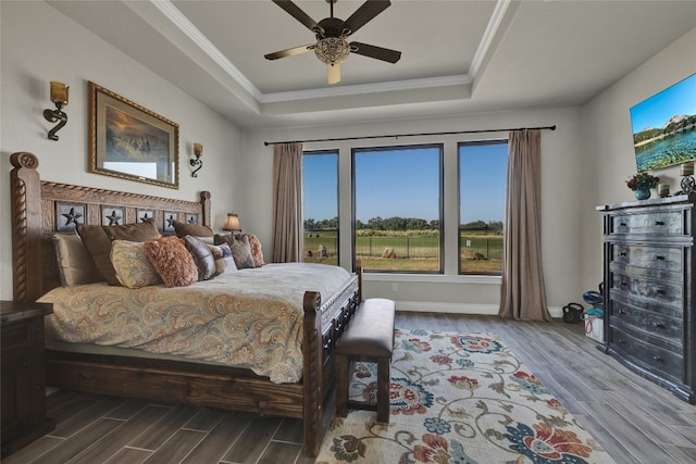 bedroom with ornamental molding, hardwood / wood-style floors, a tray ceiling, and ceiling fan