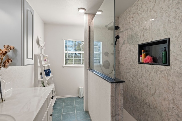 bathroom with tile patterned floors, vanity, and a tile shower