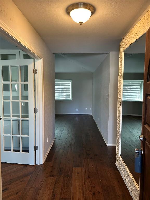 hall with a textured ceiling, a wealth of natural light, and dark hardwood / wood-style floors