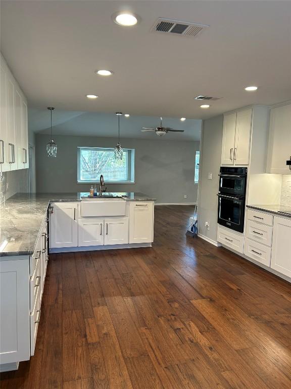 kitchen with kitchen peninsula, white cabinets, dark wood-type flooring, and sink