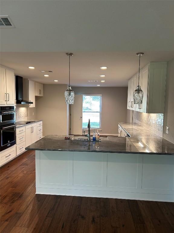 kitchen with sink, hanging light fixtures, wall chimney exhaust hood, dark hardwood / wood-style floors, and kitchen peninsula