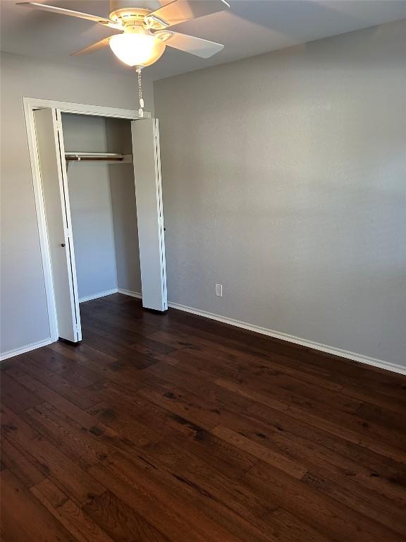 unfurnished bedroom featuring a closet, ceiling fan, and dark hardwood / wood-style flooring