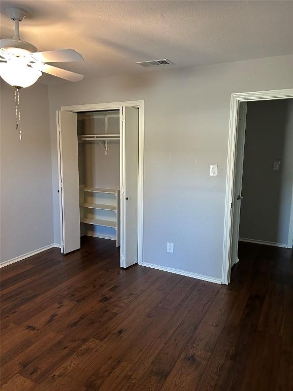 unfurnished bedroom featuring dark hardwood / wood-style flooring, ceiling fan, a closet, and a textured ceiling