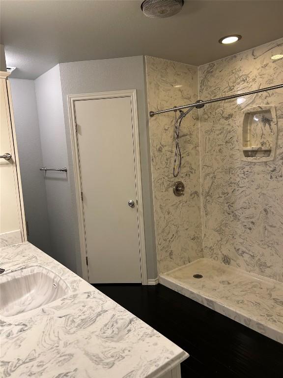 bathroom featuring hardwood / wood-style floors, vanity, and a tile shower