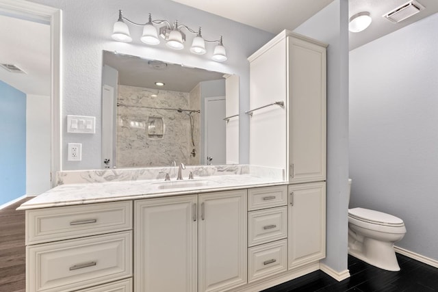 bathroom featuring toilet, a shower, wood finished floors, and visible vents