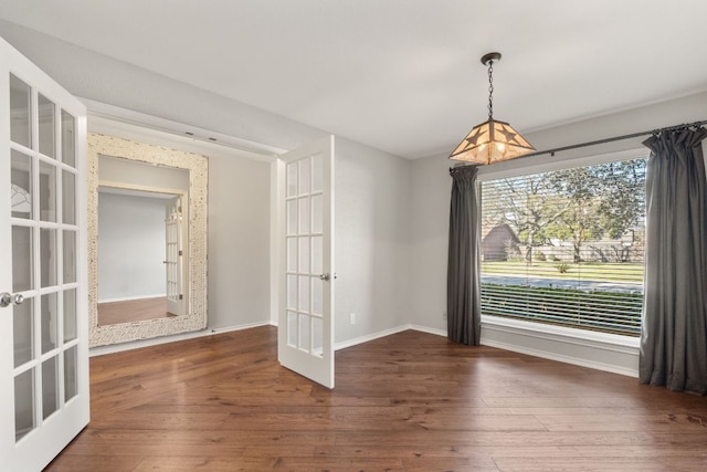 unfurnished dining area featuring french doors, hardwood / wood-style floors, and baseboards