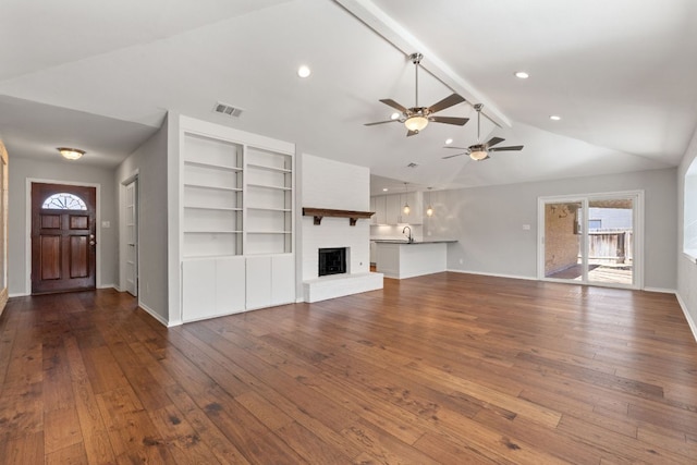 unfurnished living room featuring vaulted ceiling with beams, plenty of natural light, wood-type flooring, and a fireplace